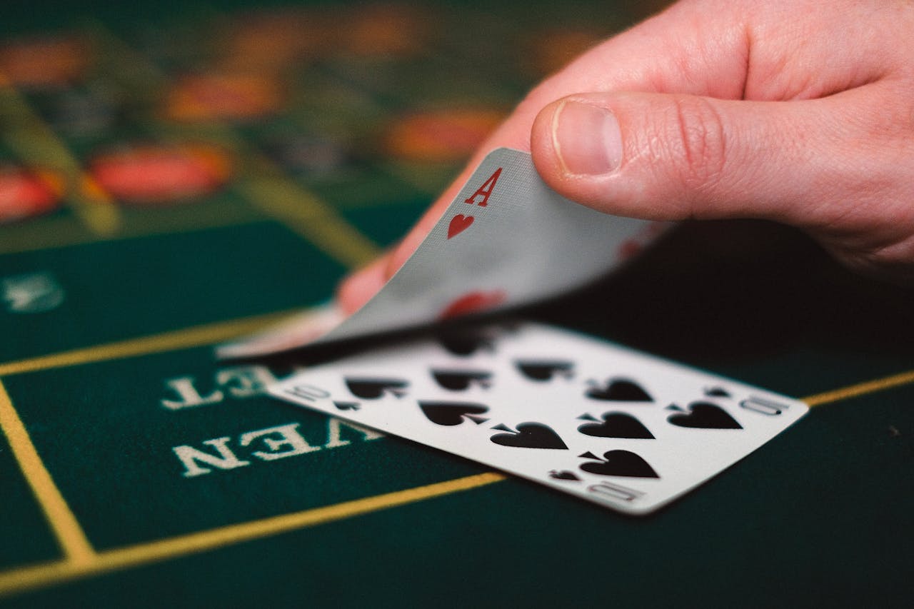 Close view of playing cards and hand on a casino table, capturing the gambling atmosphere.